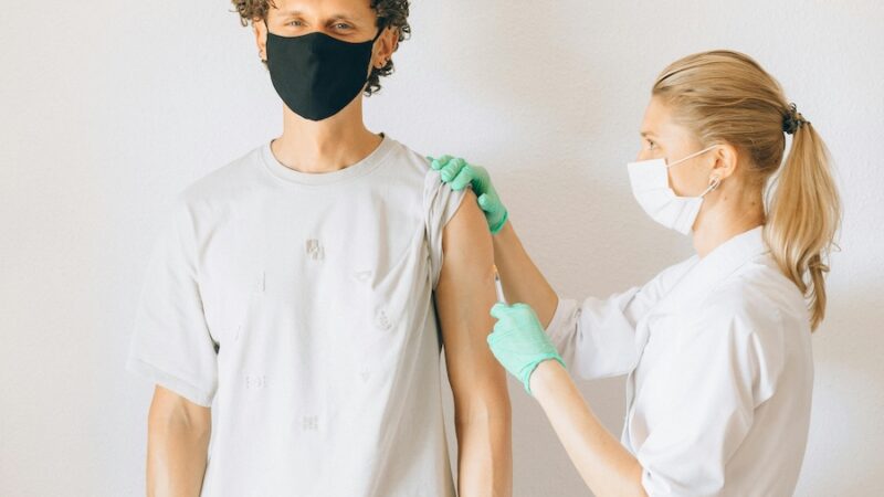 healthcare professional injecting patient with needle face masks