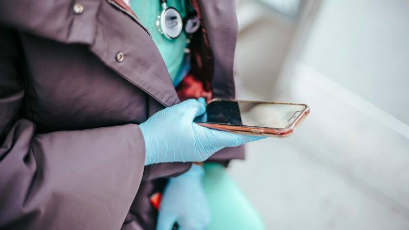 healthcare professional on mobile phone wearing latex gloves