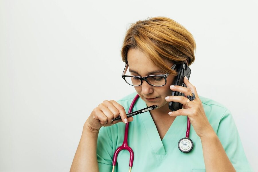 healthcare professional wearing stethoscope on mobile phone with pen